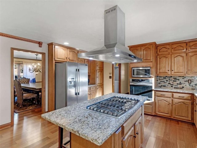 kitchen with island range hood, tasteful backsplash, stainless steel appliances, and light wood finished floors