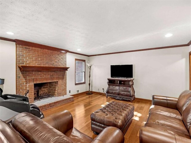 living area featuring a textured ceiling, baseboards, a brick fireplace, wood finished floors, and ornamental molding