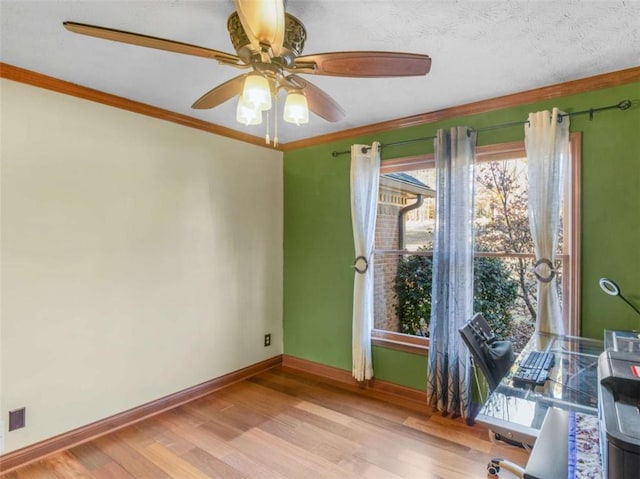 unfurnished office with light wood finished floors, baseboards, ceiling fan, and crown molding