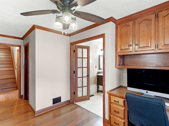 home office with light wood-type flooring, baseboards, visible vents, ceiling fan, and ornamental molding