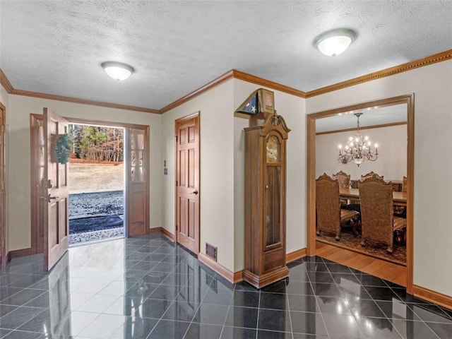 foyer entrance featuring baseboards, a textured ceiling, a notable chandelier, and crown molding
