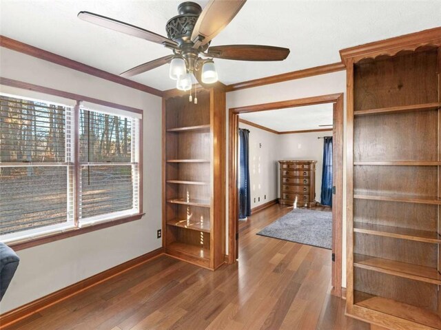 interior space featuring a ceiling fan, baseboards, ornamental molding, and wood finished floors