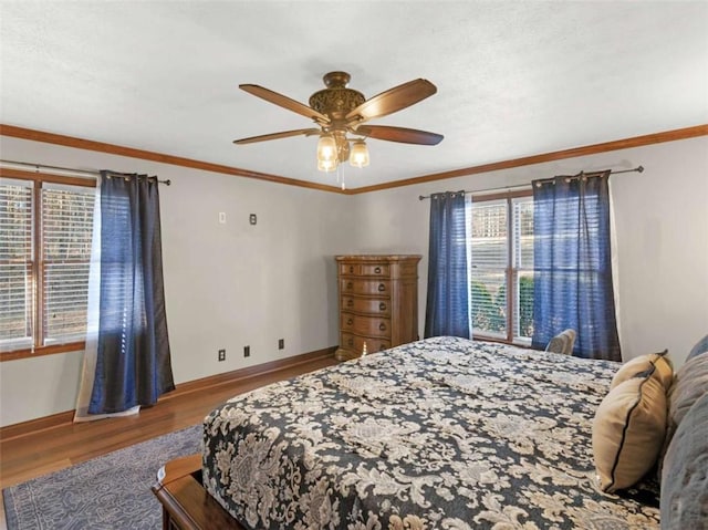 bedroom with wood finished floors, ornamental molding, baseboards, and ceiling fan