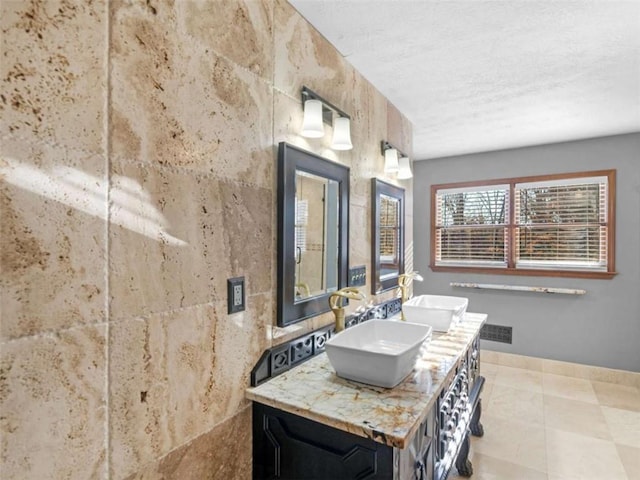 full bathroom featuring double vanity, a textured ceiling, tile patterned flooring, and a sink