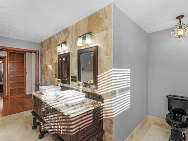 bathroom with tile walls, vanity, and an inviting chandelier