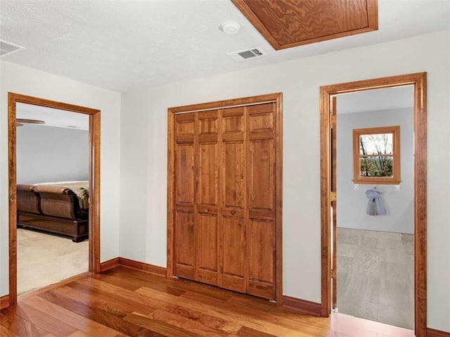 unfurnished bedroom featuring a closet, wood finished floors, visible vents, and baseboards