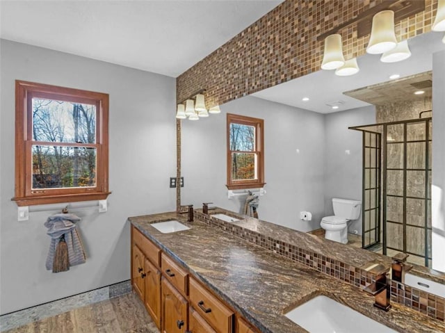 bathroom featuring toilet, wood finished floors, a sink, and a stall shower