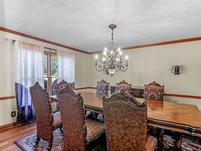 dining space featuring baseboards, wood finished floors, a textured ceiling, and a notable chandelier