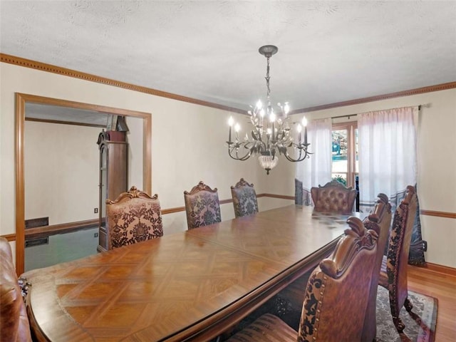 dining room featuring baseboards, crown molding, wood finished floors, and a chandelier