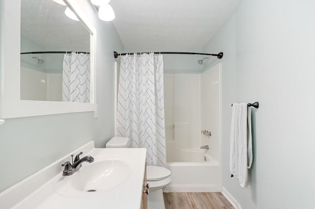 full bathroom featuring toilet, vanity, wood-type flooring, a textured ceiling, and shower / bath combo with shower curtain