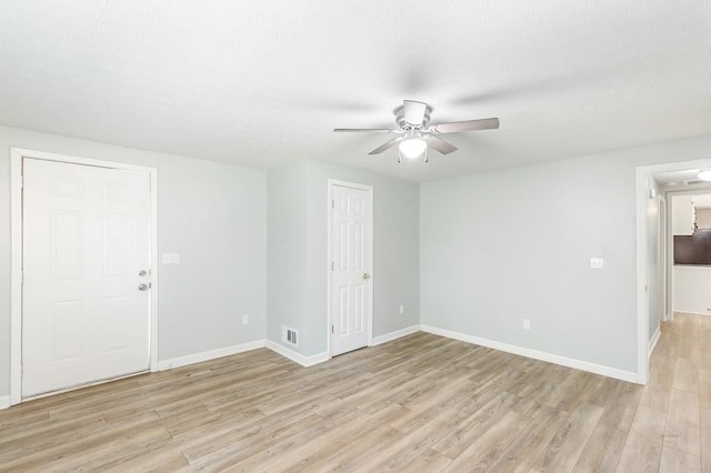 spare room with a textured ceiling, ceiling fan, and light hardwood / wood-style floors