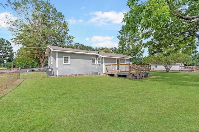 rear view of house with a deck, central air condition unit, and a yard