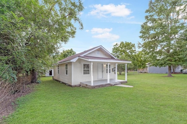 rear view of house with covered porch and a lawn