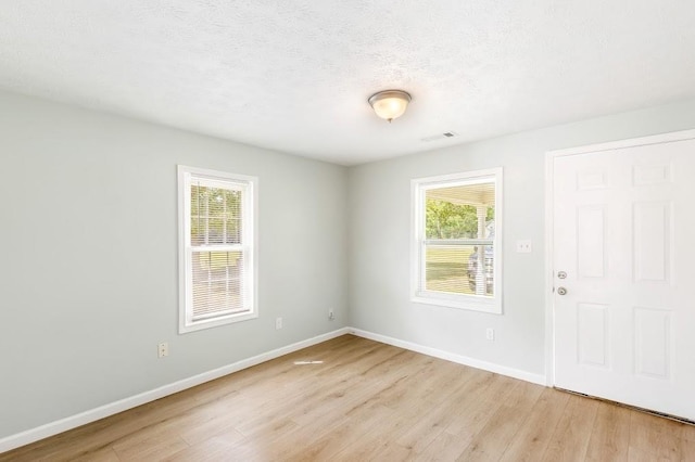 unfurnished room featuring a textured ceiling and light hardwood / wood-style floors