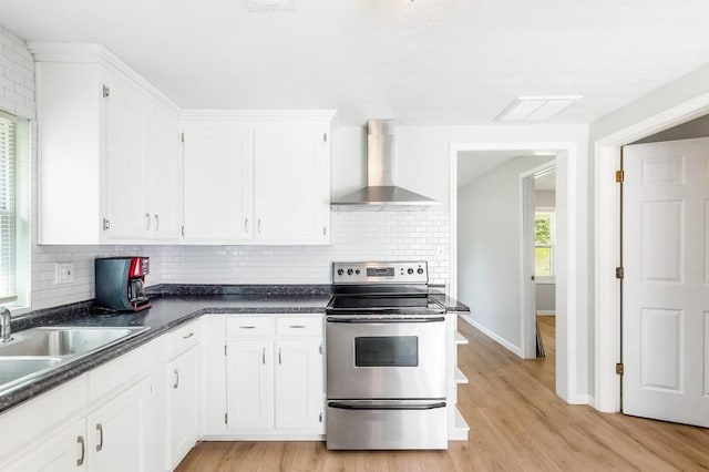 kitchen with white cabinetry, stainless steel electric range oven, wall chimney exhaust hood, and tasteful backsplash