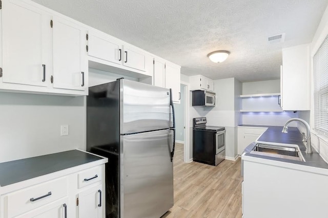 kitchen featuring light hardwood / wood-style floors, appliances with stainless steel finishes, a textured ceiling, white cabinets, and sink