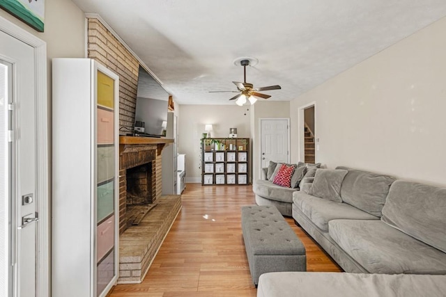 living room with ceiling fan, light hardwood / wood-style floors, and a brick fireplace