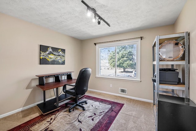 carpeted office with rail lighting and a textured ceiling