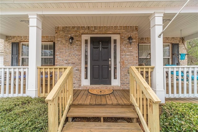 property entrance with brick siding and a porch