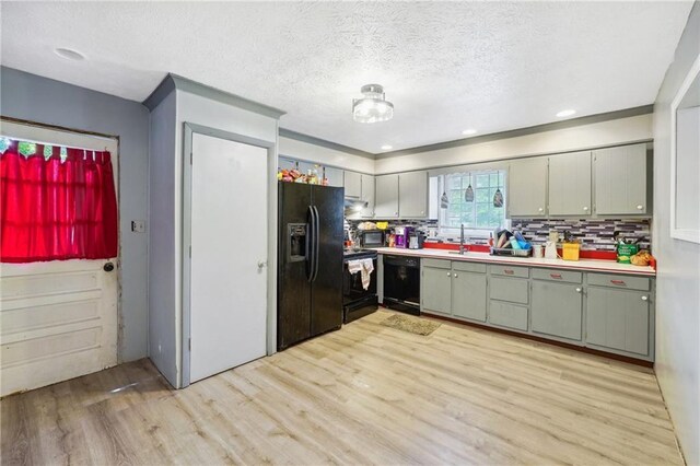 kitchen with backsplash, light countertops, light wood-style floors, and black appliances