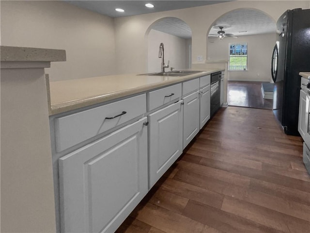 kitchen featuring white cabinets, black appliances, sink, ceiling fan, and dark hardwood / wood-style flooring