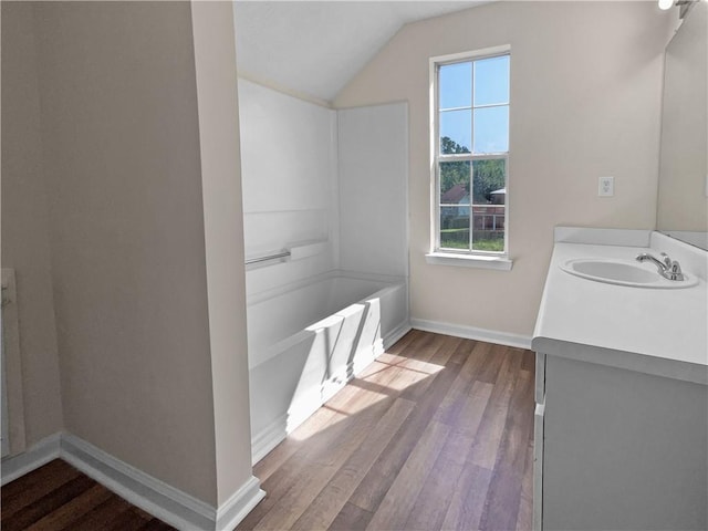 bathroom featuring vanity, wood-type flooring, a wealth of natural light, and lofted ceiling