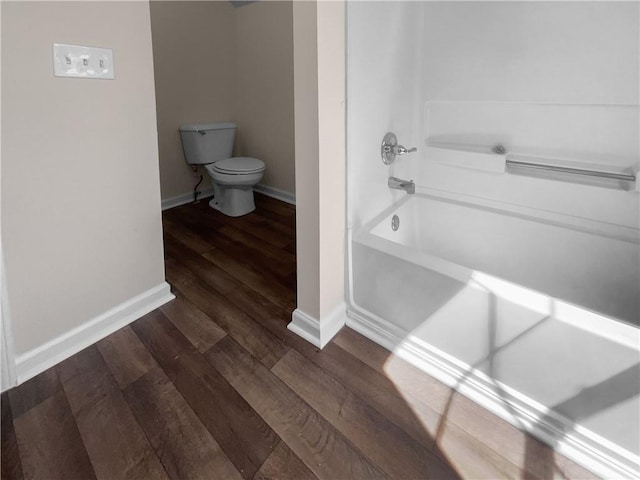 bathroom with hardwood / wood-style floors, toilet, and tub / shower combination