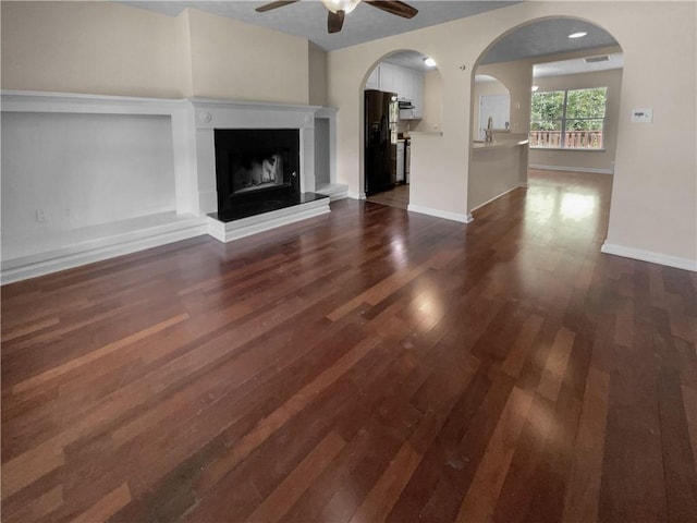 unfurnished living room with ceiling fan, dark hardwood / wood-style flooring, and sink