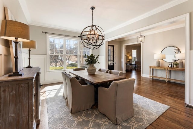 dining area with a chandelier, wainscoting, crown molding, and dark wood-style flooring