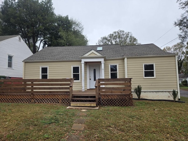 rear view of house with a deck, a lawn, and roof with shingles