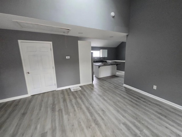 unfurnished living room featuring attic access, baseboards, and wood finished floors