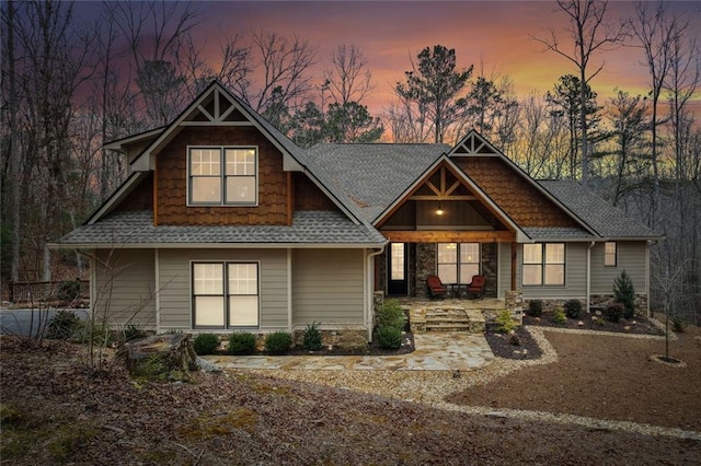 craftsman house with a shingled roof and a patio