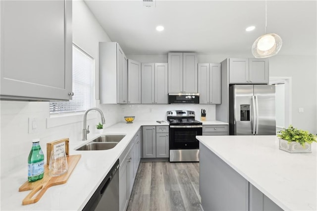 kitchen with light wood finished floors, appliances with stainless steel finishes, gray cabinets, light countertops, and a sink