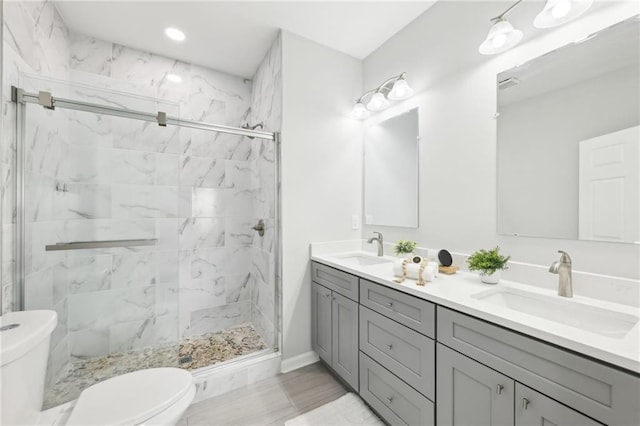 full bath with a marble finish shower, a sink, and toilet