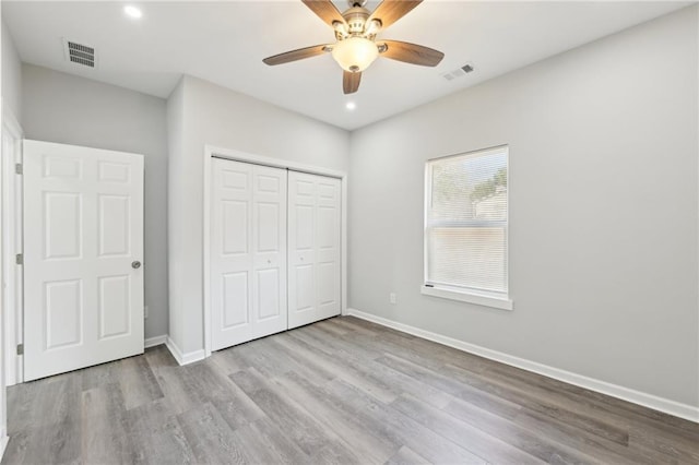 unfurnished bedroom with baseboards, a closet, visible vents, and wood finished floors