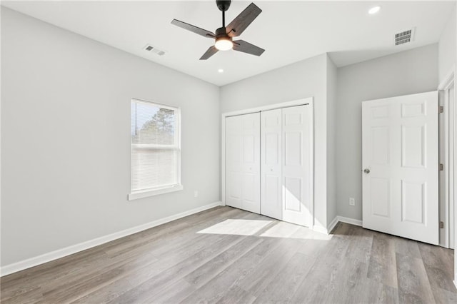 unfurnished bedroom with a closet, wood finished floors, visible vents, and baseboards