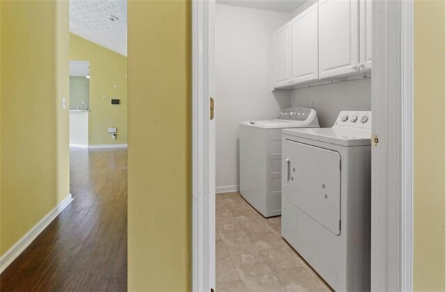 3971 Canebrake Ln, Douglasville, GA 30134 - laundry room featuring washer and clothes dryer, cabinet space, baseboards, and light wood-style floors
