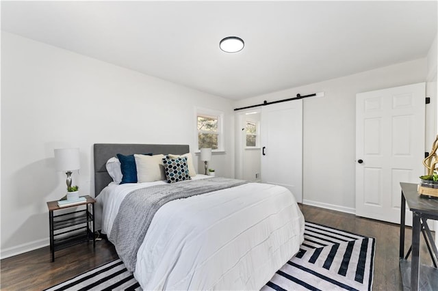 bedroom with a barn door and dark wood-type flooring