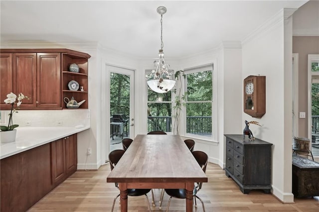 dining area with light wood finished floors, a chandelier, baseboards, and ornamental molding