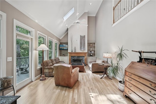 living area featuring high vaulted ceiling, wood finished floors, ceiling fan, baseboards, and a high end fireplace