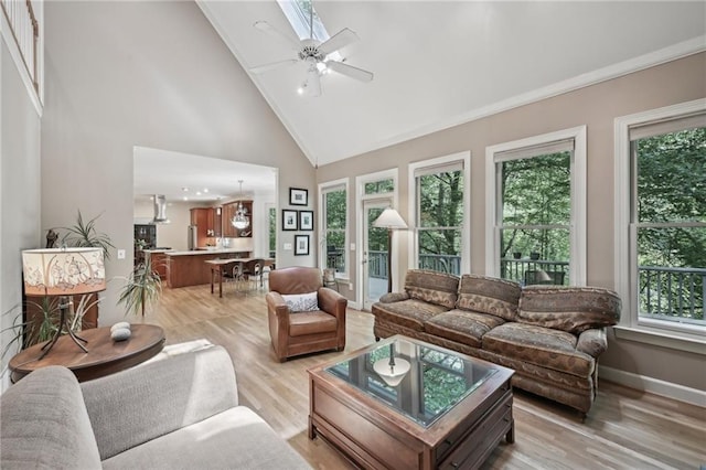 living room featuring high vaulted ceiling, ceiling fan, light wood-type flooring, and baseboards