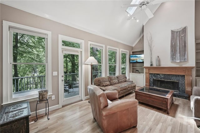 living room with ceiling fan, healthy amount of natural light, wood finished floors, and high vaulted ceiling
