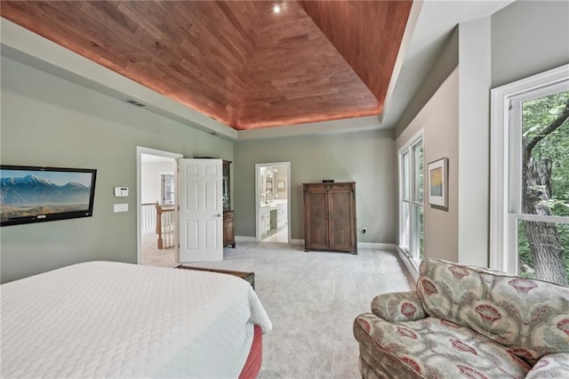 bedroom with light carpet, wood ceiling, a raised ceiling, baseboards, and ensuite bath