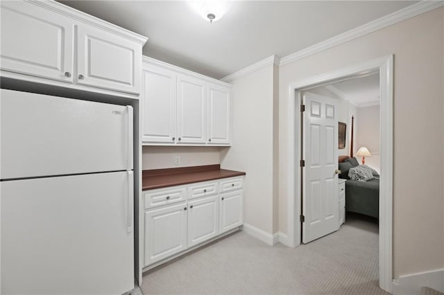 kitchen featuring freestanding refrigerator, dark countertops, light carpet, white cabinets, and baseboards