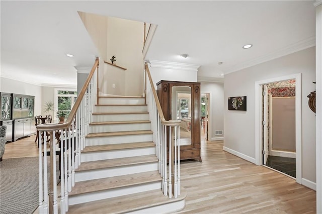 stairway with ornamental molding, recessed lighting, wood finished floors, and baseboards