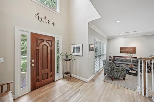 foyer featuring wood finished floors, baseboards, ornamental molding, and rail lighting