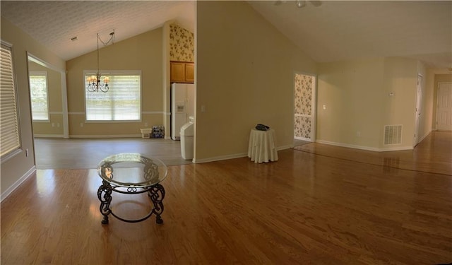 964 Village View Cir, Loganville, GA 30052 - unfurnished living room with a chandelier, wood finished floors, baseboards, and high vaulted ceiling