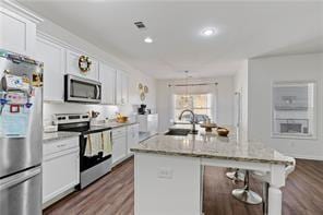 6547 River Station Dr, Lula, GA 30554 - kitchen featuring appliances with stainless steel finishes, a kitchen island with sink, white cabinetry, dark wood finished floors, and recessed lighting