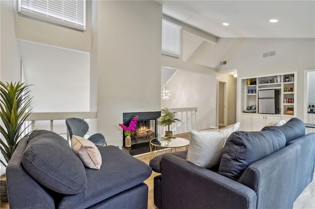 living room with a multi sided fireplace, high vaulted ceiling, and beamed ceiling