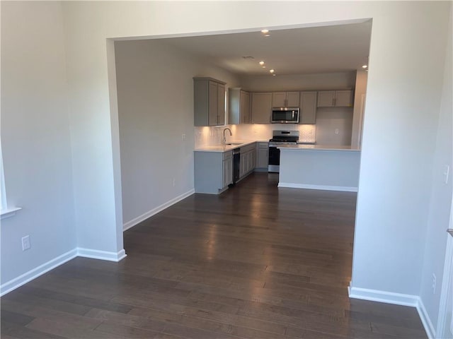 kitchen with a sink, stainless steel appliances, gray cabinetry, and light countertops